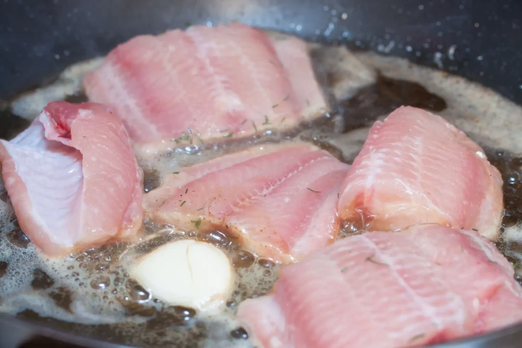 Welsfilets braten in der Pfanne mit Butter und Knoblauch